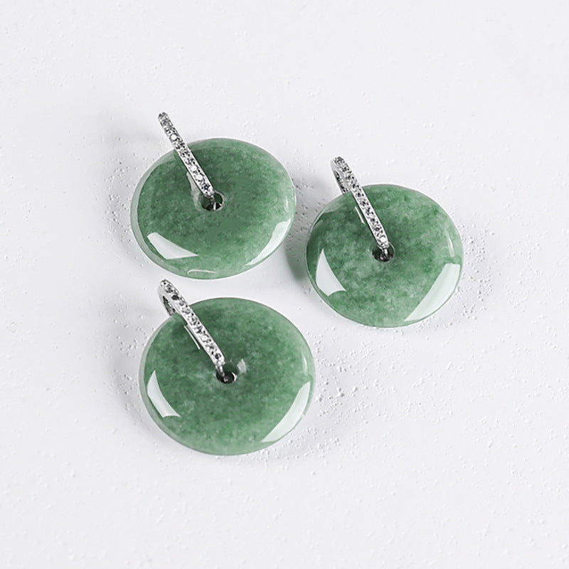 Three unique variations of natural green jadeite peace buckle pendants showcasing the organic color variations of the authentic stone.