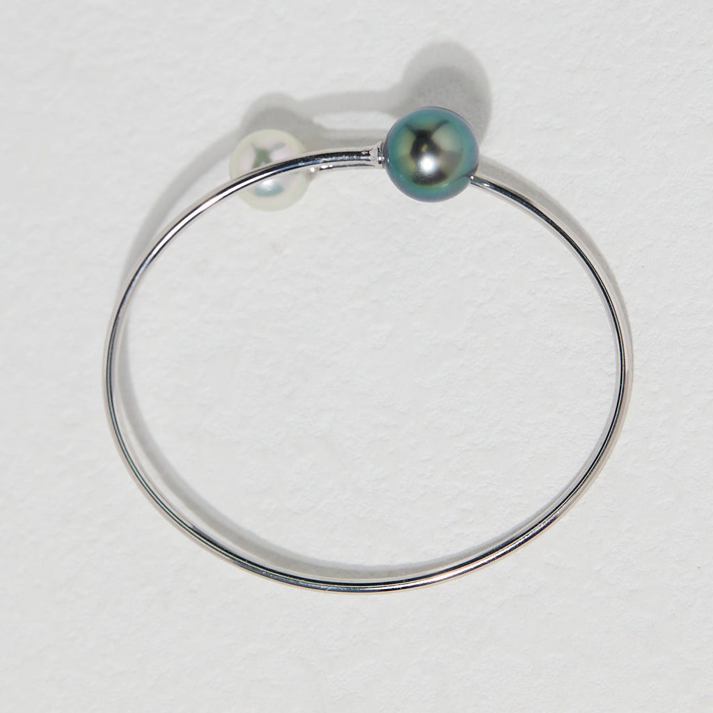 BoxUnboxed 18K white gold bypass bangle with a dark Tahitian pearl and a white Akoya pearl.
