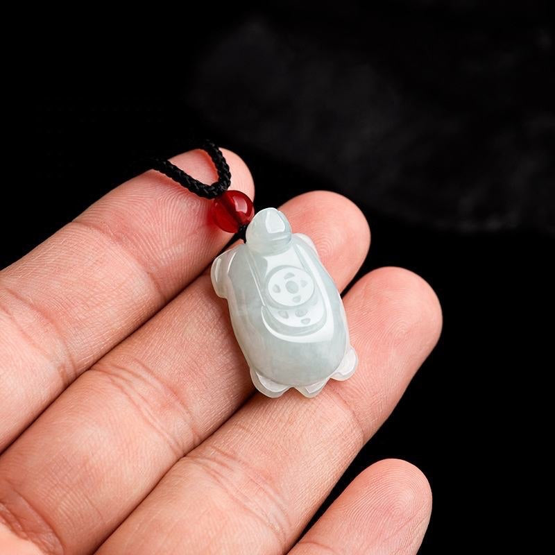 BoxUnboxed hand-carved natural jadeite turtle pendant with a red bead on a black cord for longevity and protection.