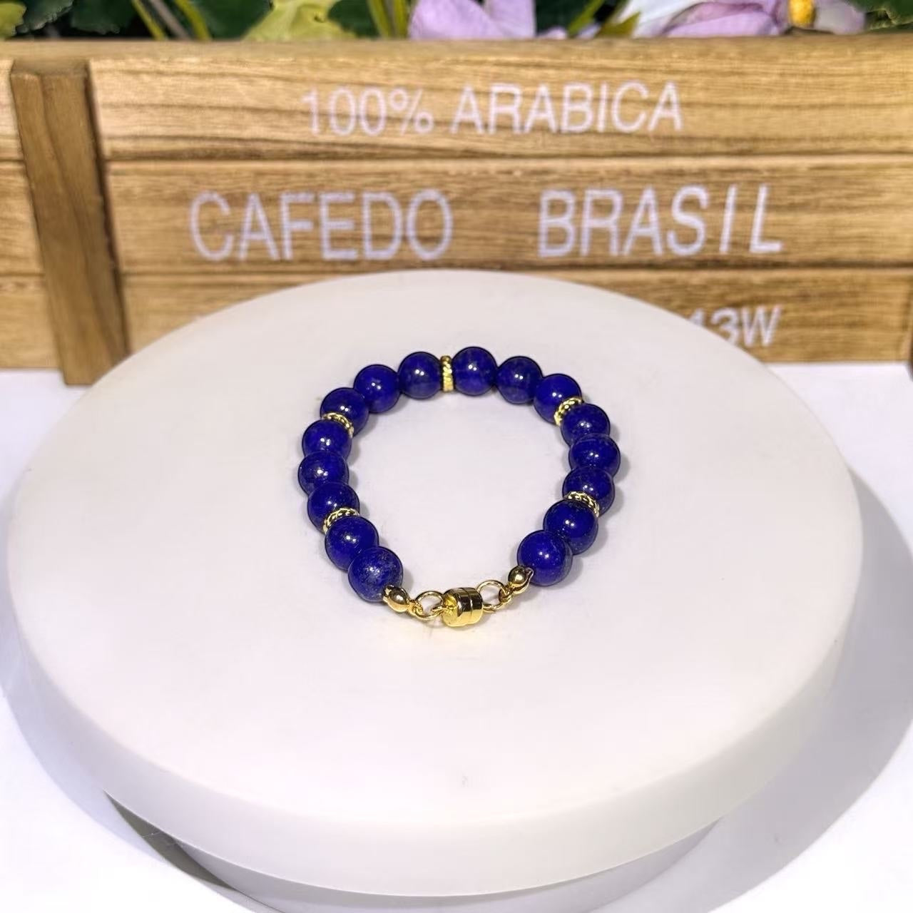 BoxUnboxed natural Afghan Lapis Lazuli bracelet with gold-plated accents and a gold magnetic clasp on a white stand.