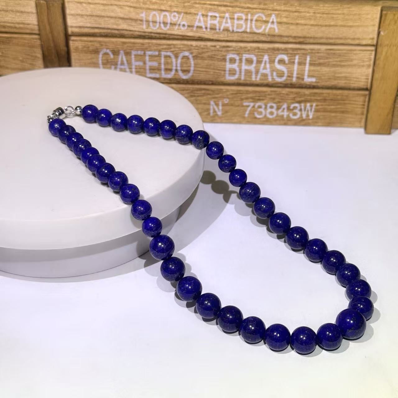 BoxUnboxed natural Afghan Lapis Lazuli beaded necklace with deep indigo stones and metallic clasp on a white display stand