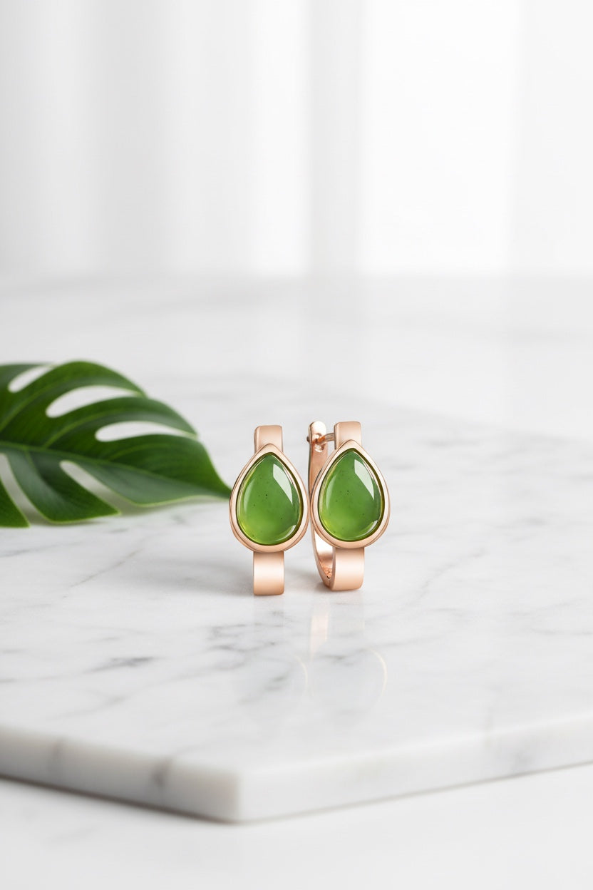 BoxUnboxed teardrop nephrite jade huggie earrings in rose gold plated sterling silver on a marble surface.