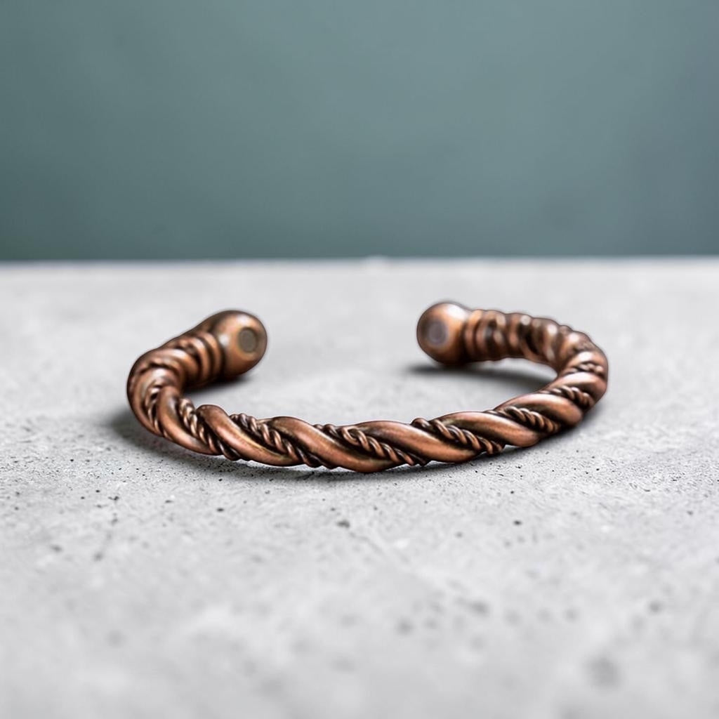 BoxUnboxed pure copper twisted wire open cuff bracelet with magnetic end caps on a grey textured surface.
